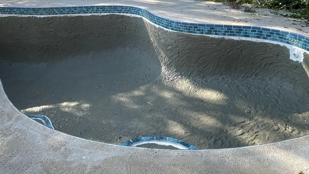 Swimming pool during replastering process with surface prepared and old plaster removed before new finish is applied.