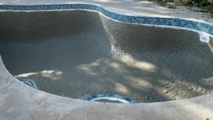 Swimming pool during replastering process with surface prepared and old plaster removed before new finish is applied.