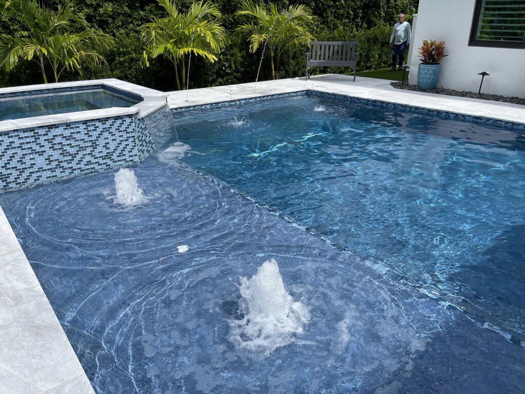 Luxury pool with spa and water features in Palm Beach Gardens, showing benefits of regular pool cleaning service