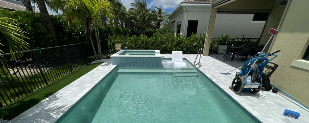 Residential pool with vacuum and test kit on deck, illustrating when to call a pool professional for expert maintenance