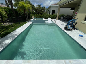 Residential pool with vacuum and test kit on deck, illustrating when to call a pool professional for expert maintenance