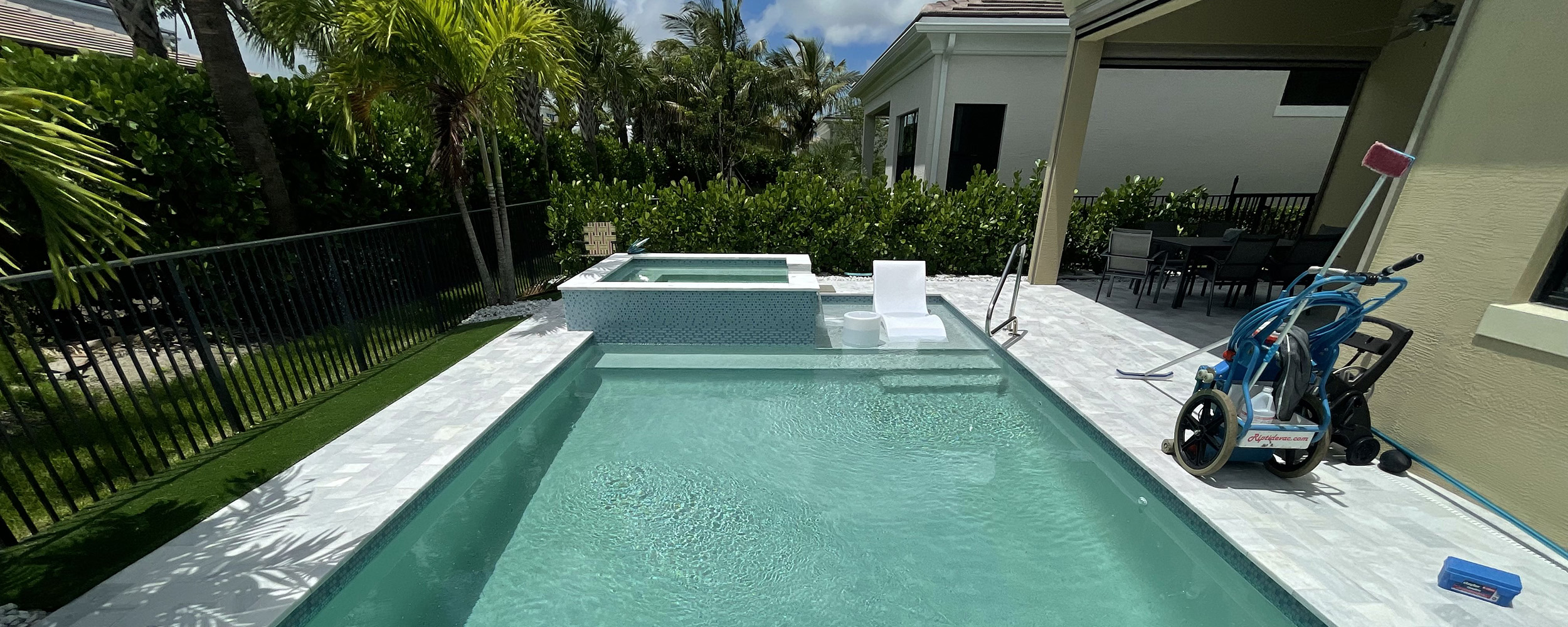 Residential pool with vacuum and test kit on deck, illustrating when to call a pool professional for expert maintenance
