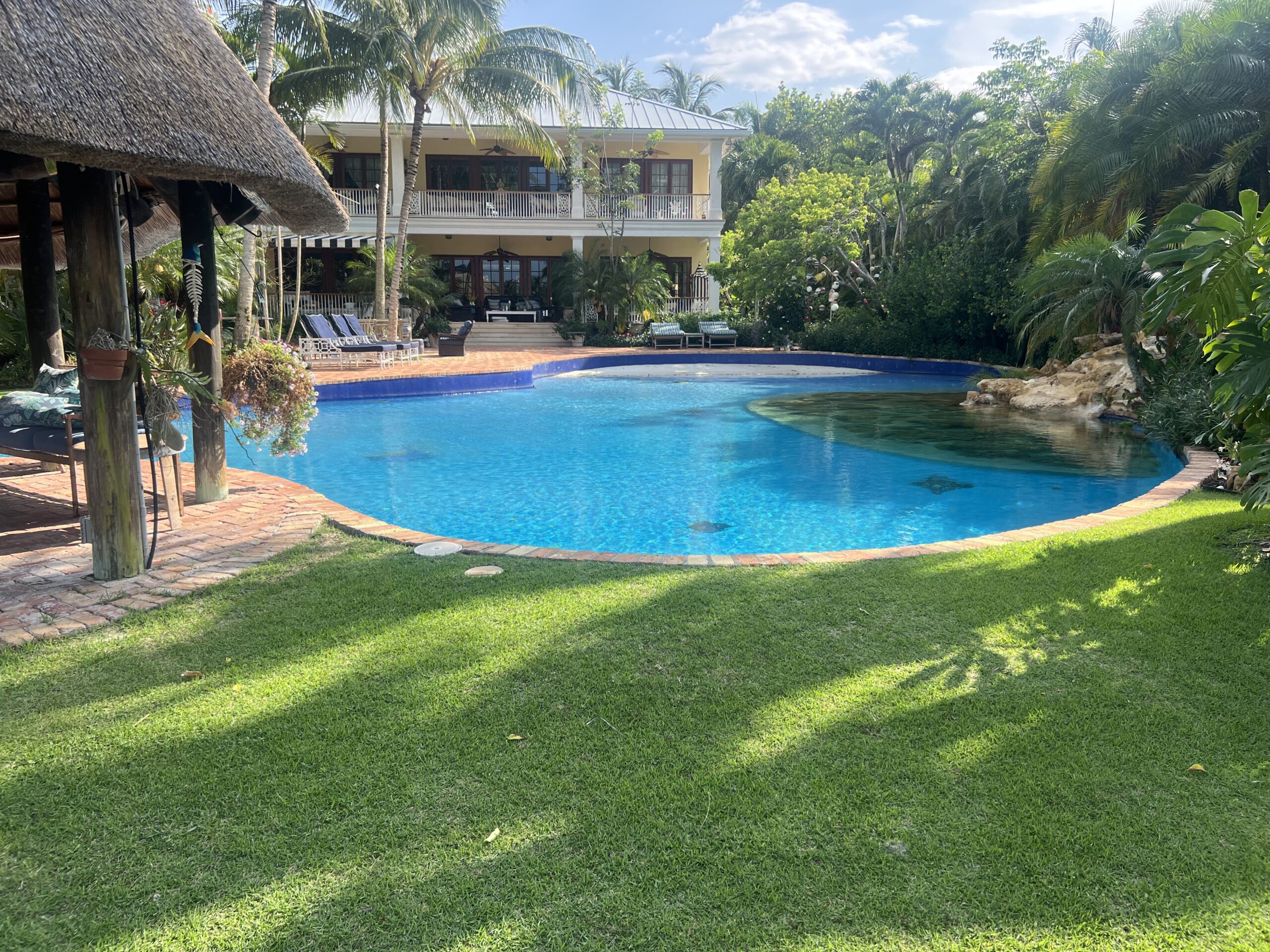 A clean, well-maintained backyard with a pool, tiki hut, and lush landscaping — showing the result of home maintenance without feeling overwhelmed.