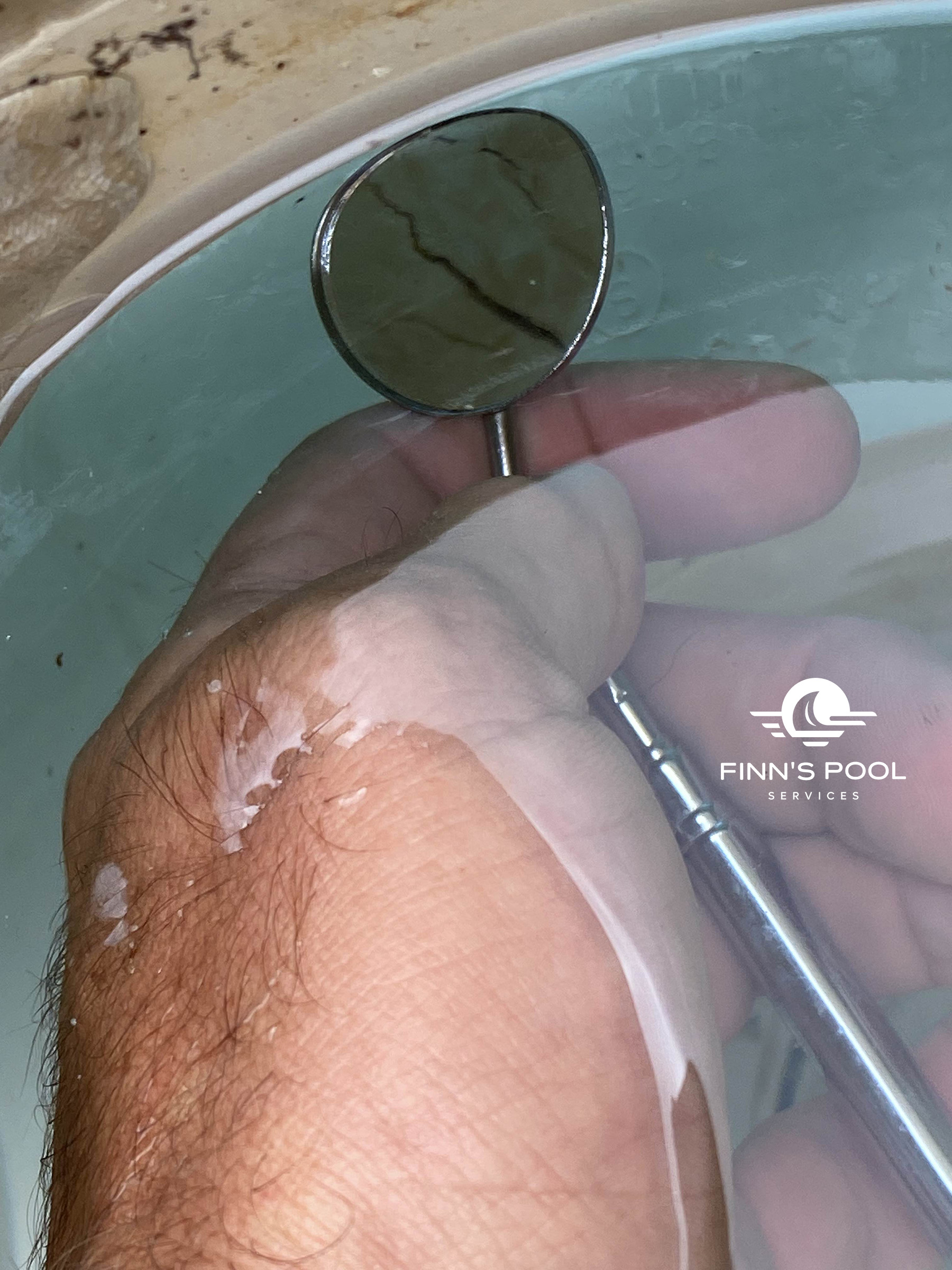 Magnifying glass highlighting cracks during pool leak detection inside a swimming pool