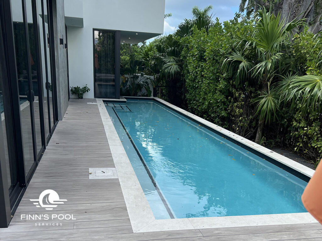 A modern swimming pool surrounded by lush greenery, highlighting how pool resurfacing enhances an outdoor living space in Florida.