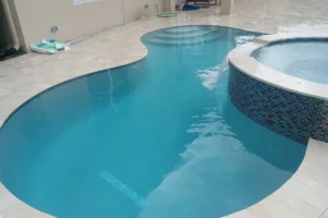 Swimming pool in South Florida during rainy weather with cloudy blue water and visible rain droplets on the surface.