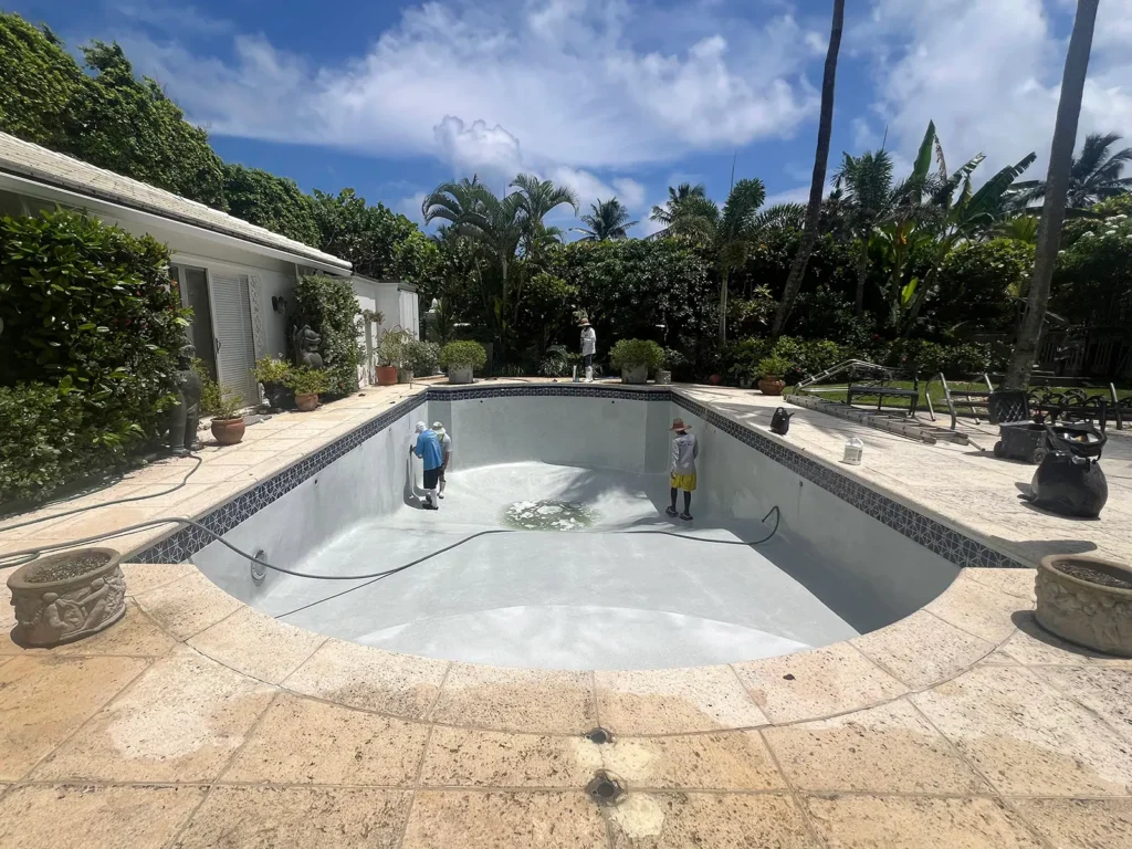 Pool resurfacing crew working inside a drained South Florida swimming pool